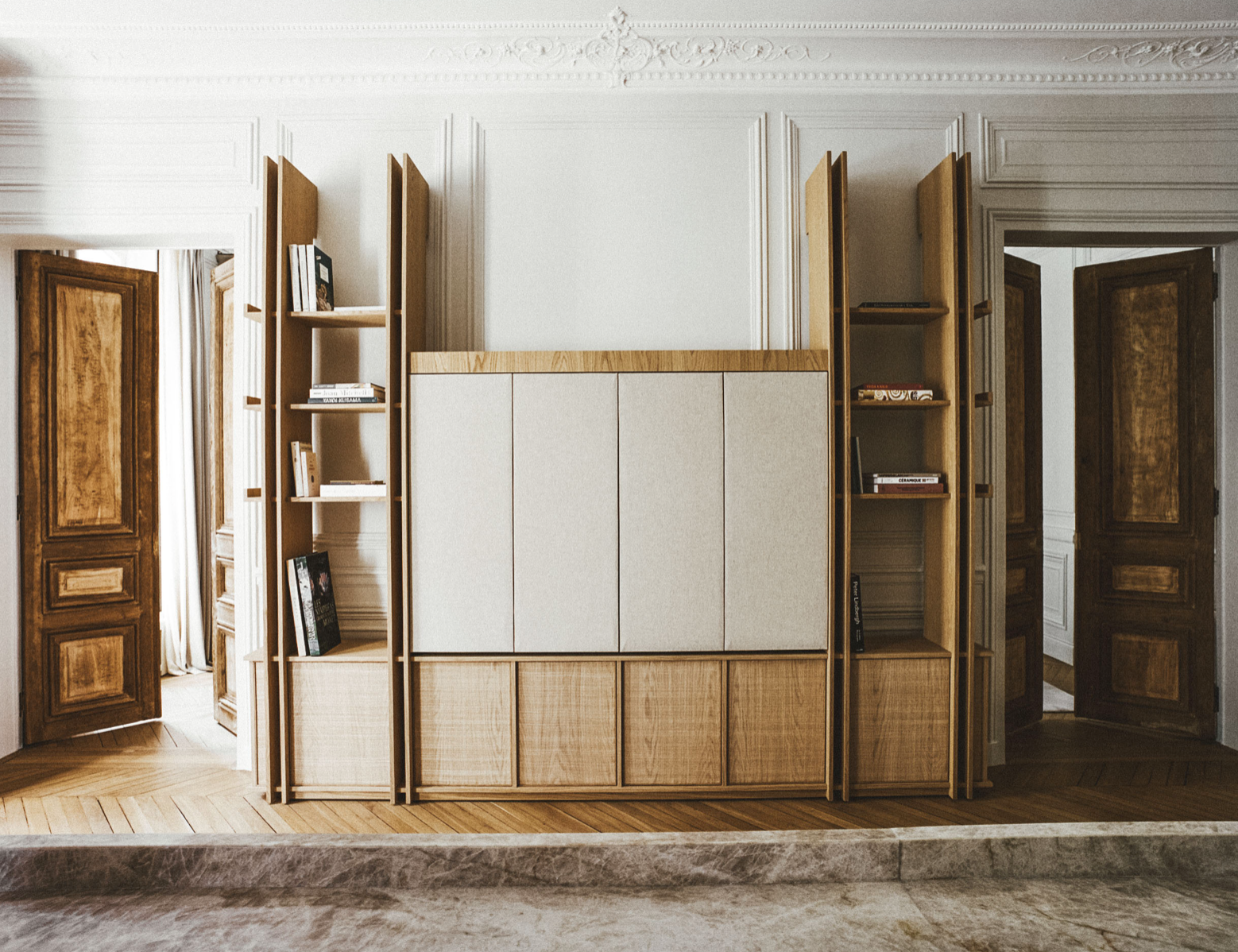 A still room — panelled cabinet, herringbone floor, soft daylight.